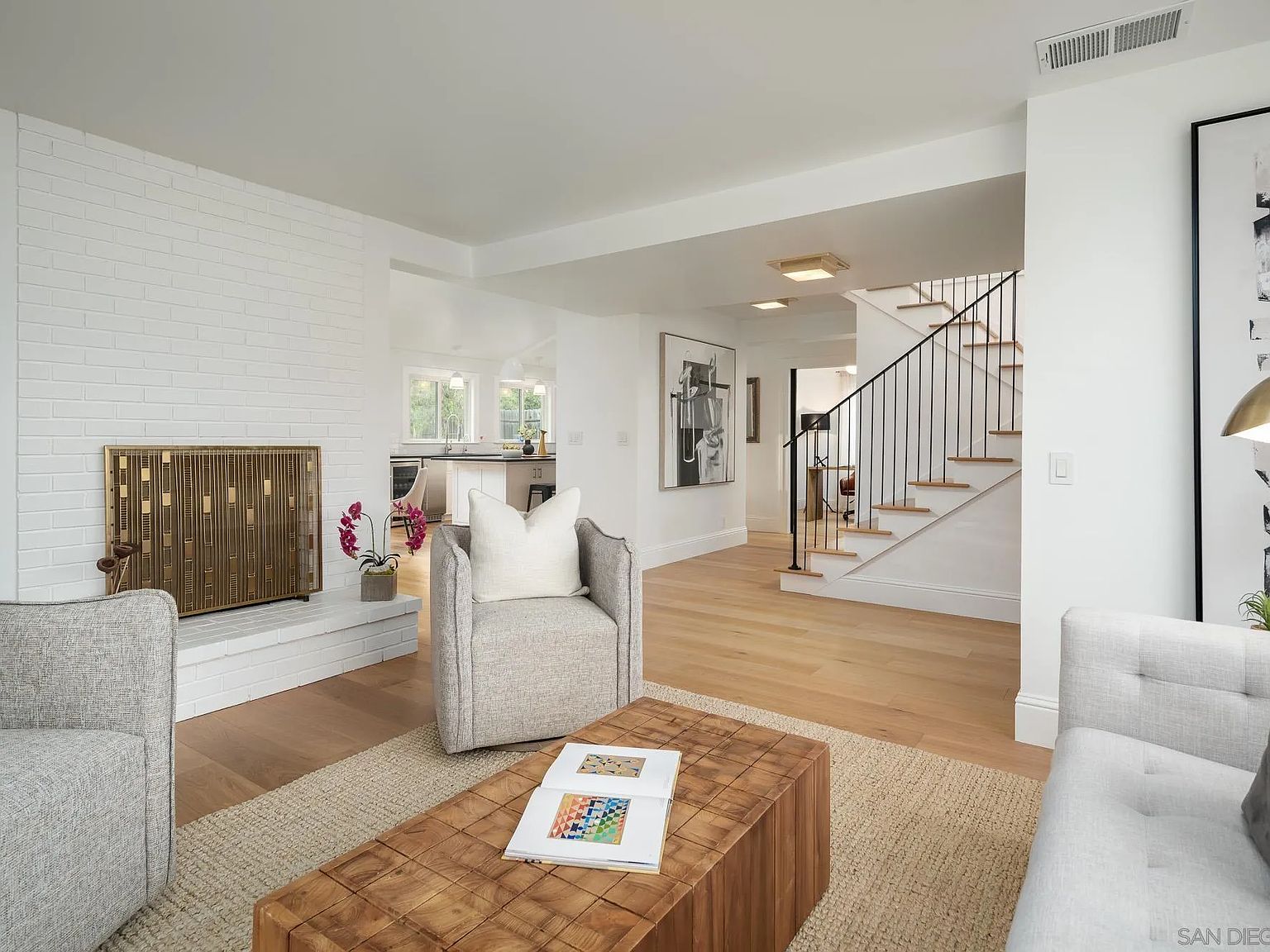 Living room with white brick fireplace and open staircase