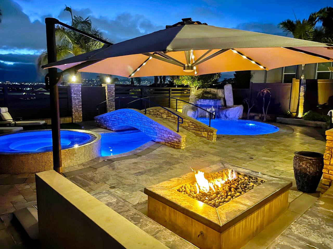 Illuminated pool, spa, and fire table on the evening terrace