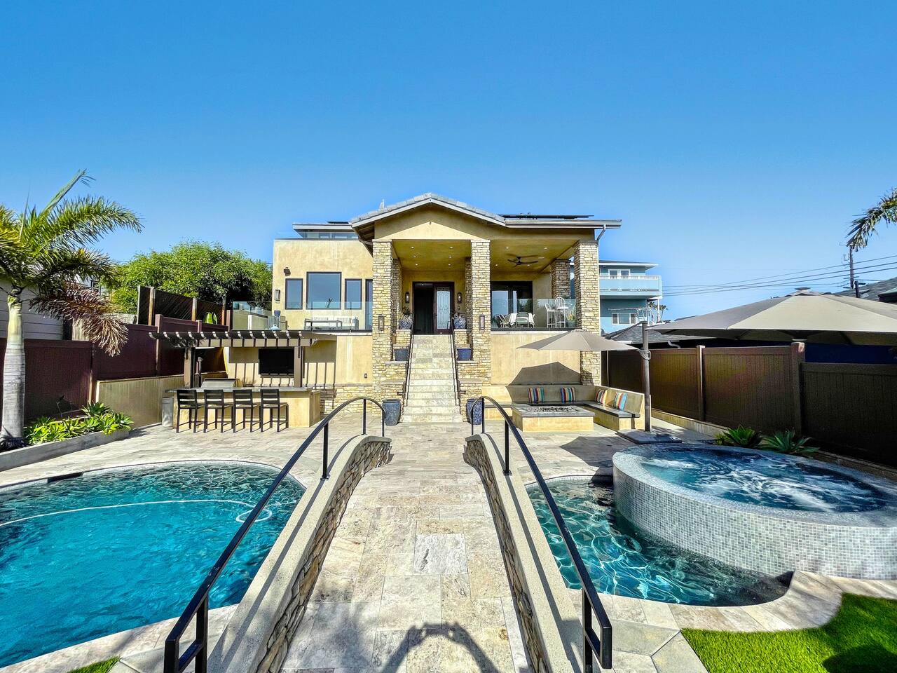 Pool and spa with outdoor bar seating below the residence